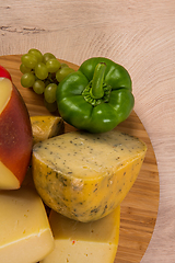 Image showing Bosnian traditional cheese served on a wooden container with peppers, parade and onions isolated on a white background