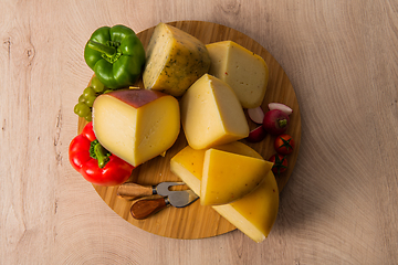 Image showing Bosnian traditional cheese served on a wooden container with peppers, parade and onions isolated on a white background