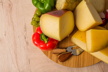 Image showing Bosnian traditional cheese served on a wooden container with peppers, parade and onions isolated on a white background