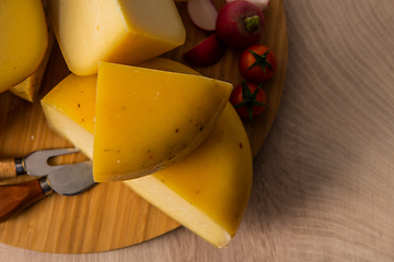 Image showing Bosnian traditional cheese served on a wooden container with peppers, parade and onions isolated on a white background