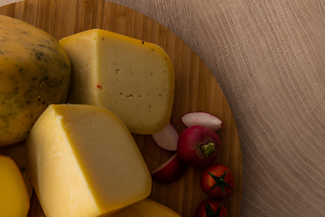 Image showing Bosnian traditional cheese served on a wooden container with peppers, parade and onions isolated on a white background