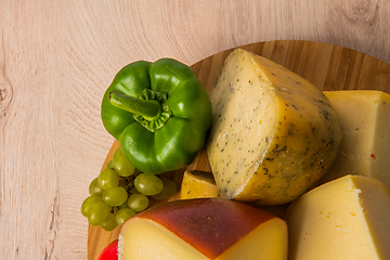 Image showing Bosnian traditional cheese served on a wooden container with peppers, parade and onions isolated on a white background