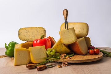 Image showing Bosnian traditional cheese served on a wooden container with peppers, parade and onions isolated on a white background