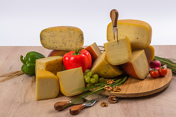 Image showing Bosnian traditional cheese served on a wooden container with peppers, parade and onions isolated on a white background