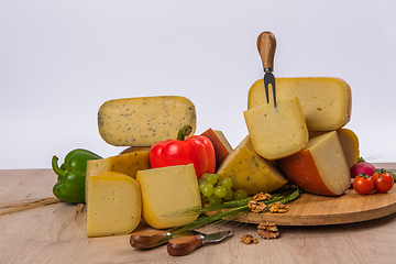 Image showing Bosnian traditional cheese served on a wooden container with peppers, parade and onions isolated on a white background