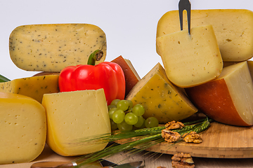 Image showing Bosnian traditional cheese served on a wooden container with peppers, parade and onions isolated on a white background