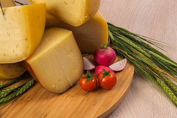 Image showing Bosnian traditional cheese served on a wooden container with peppers, parade and onions isolated on a white background