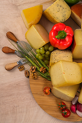 Image showing Bosnian traditional cheese served on a wooden container with peppers, parade and onions isolated on a white background