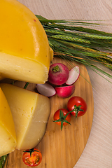 Image showing Bosnian traditional cheese served on a wooden container with peppers, parade and onions isolated on a white background