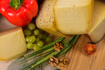 Image showing Bosnian traditional cheese served on a wooden container with peppers, parade and onions isolated on a white background