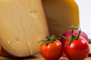 Image showing Bosnian traditional cheese served on a wooden container with peppers, parade and onions isolated on a white background