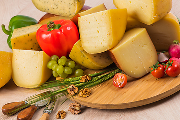 Image showing Bosnian traditional cheese served on a wooden container with peppers, parade and onions isolated on a white background