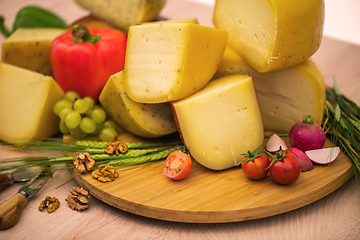 Image showing Bosnian traditional cheese served on a wooden container with peppers, parade and onions isolated on a white background