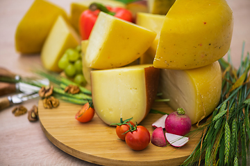 Image showing Bosnian traditional cheese served on a wooden container with peppers, parade and onions isolated on a white background