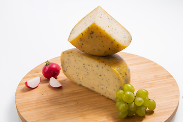 Image showing Bosnian traditional cheese served on a wooden container with peppers, parade and onions isolated on a white background