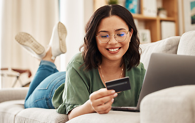 Image showing Relax, laptop and credit card, happy woman on sofa in living room for internet banking in home for online shopping. Ecommerce payment, smile and cashback, girl on couch with computer and website sale