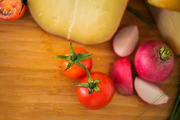 Image showing Bosnian traditional cheese served on a wooden container with peppers, parade and onions isolated on a white background