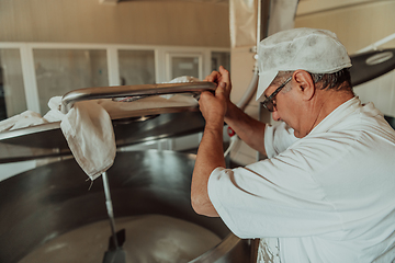 Image showing Man mixing milk in the stainless tank during the fermentation process at the cheese manufacturing