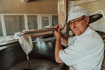 Image showing Man mixing milk in the stainless tank during the fermentation process at the cheese manufacturing