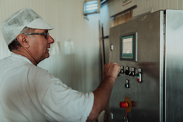 Image showing Cheese maker working in the modern industry on machines that are using for the machining of fresh cheese