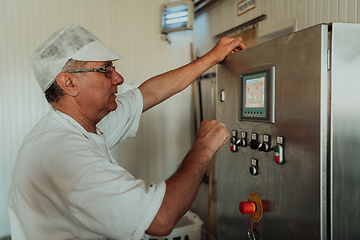 Image showing Cheese maker working in the modern industry on machines that are using for the machining of fresh cheese