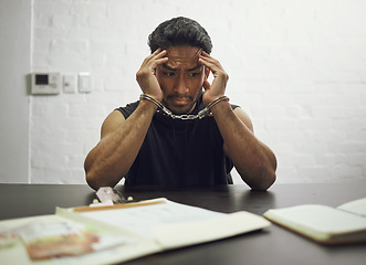 Image showing Man, criminal and handcuffs in fear for interrogation, drugs or crime in arrest on table in room. Worried male person, gangster or suspect in jail, justice or guilty fraud, theft or illegal substance