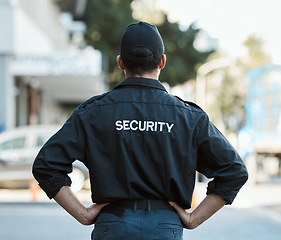 Image showing Man, back and security guard in city for safety protection, law enforcement or outdoor emergency. Rear view of male person, police or officer standing ready for crime control to protect and serve