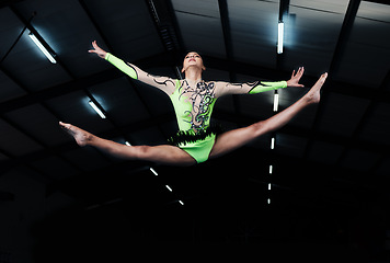 Image showing Woman, jump and gymnastics with fitness and competition, action and body with performance in arena. Female gymnast in air, athlete exercise with flexibility and health for sports, flying and acrobat