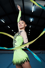 Image showing Happy, woman and rhythmic gymnastics with ribbon in gym, creativity and action, performance and fitness. Competition, athlete and female gymnast, dance and art with body, routine and energy at arena