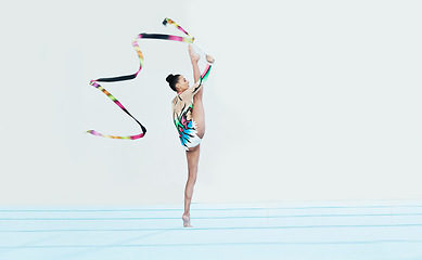 Image showing Gymnastics performance, woman and ribbon with legs split for competition, sport and show on studio floor. Gymnast, athlete girl or professional dancer for balance, training or contest for creativity