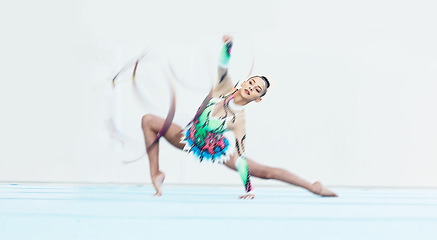 Image showing Gymnastics performance, woman and ribbon on floor for competition, sport or fitness with stretching. Gymnast, athlete girl and professional dancer with balance, training or contest with motion blur
