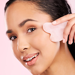 Image showing Natural beauty, face massage and woman with a gua sha, skin glow and cosmetics. Portrait of a young aesthetic female model happy with self care, facial or dermatology results on a pink background