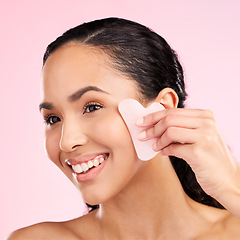 Image showing Facial massage, natural beauty and woman with a gua sha, skin glow and cosmetics. Face of a young aesthetic female model happy with self care and dermatology stone results on a pink background