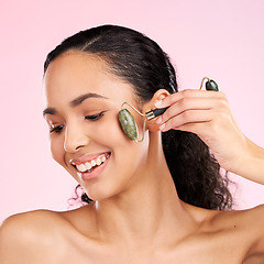 Image showing Natural beauty, facial roller and woman with skin glow, health or wellness cosmetics. Face of a young aesthetic female model happy with dermatology or skincare massage results on a pink background