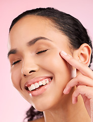 Image showing Skin, beauty cream and face of a woman in studio for cosmetics, dermatology and glow. Headshot, moisturizer and natural skincare of a young female aesthetic model on a pink background with a smile