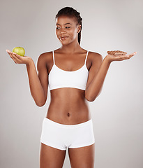 Image showing Choice, apple and black woman with chocolate for health decision and isolated in gray studio background with junk food. Balance, wellness and African person holding fruit and sweet, dessert or candy