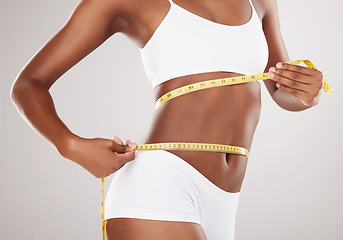 Image showing Tape measure, diet and stomach or body of woman for health and wellness on studio background. Fitness, progress or underwear and waist of aesthetic female model for weight loss, balance or motivation