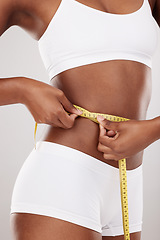 Image showing Tape measure, waist and stomach or body of woman for health and wellness on white background in studio. Fitness, progress and underwear of model on diet for weight loss goals, balance or motivation