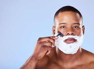Image showing Beard hair removal, cream and portrait of a black man on a blue background for grooming and beauty. Serious, spa and face of an African person with a razor for shaving and cleaning on the face