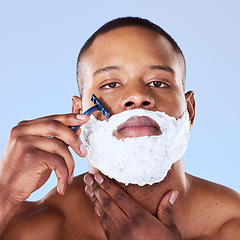 Image showing Shaving beard, cream and portrait of a black man on a blue background for grooming and beauty. Serious, spa and face of an African person with a razor for hair removal and cleaning on the face