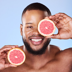 Image showing Black man, grapefruit and studio portrait for skincare, detox or vitamin c for smile, health or wellness by background. African guy, model and citrus fruit in hands by eye, facial beauty or nutrition