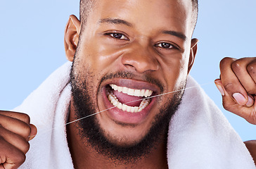Image showing Portrait, man and floss teeth in studio, health dental and self care of gum gingivitis. Face of black male model, thread or cleaning mouth for fresh breath, tooth hygiene or plaque on blue background