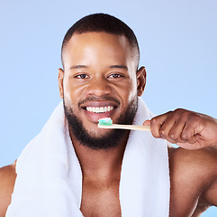 Image showing Portrait, black man and brushing teeth in studio for dental, bamboo toothbrush and blue background. Face of male model cleaning mouth with eco friendly wooden product for fresh breath or oral hygiene