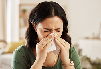 Image showing Tissue, nose and sick woman sneezing on a sofa with allergy, cold or flu in her home. Hay fever, allergy and female with viral infection, problem or health crisis in a living room with congestion