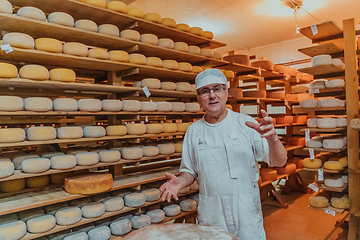 Image showing A worker at a cheese factory sorting freshly processed cheese on drying shelves