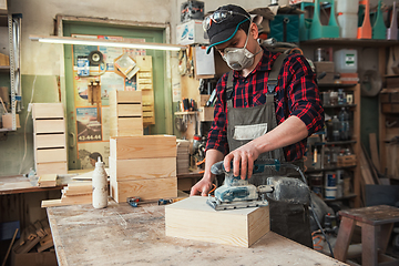 Image showing Worker grinds the wood box