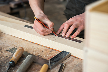 Image showing The worker makes measurements of a wooden board