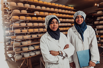 Image showing Arab business partners checking the quality of cheese in the industry and enter data into a laptop. Small business concept