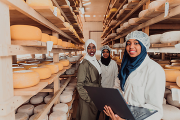 Image showing Arab business partners checking the quality of cheese in the industry and enter data into a laptop. Small business concept