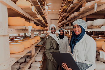 Image showing Arab business partners checking the quality of cheese in the industry and enter data into a laptop. Small business concept